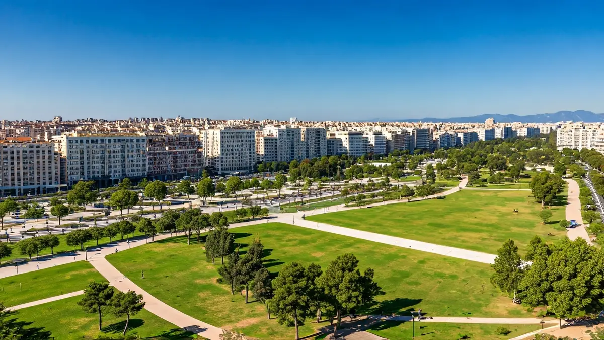 Imatge aèria d'un gran parc urbà verd que connecta diferents barris d'una ciutat mediterrània.