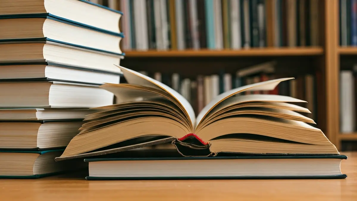 Imatge genèrica de llibres en una taula, amb un llibre obert en primer pla, en un ambient de biblioteca.
