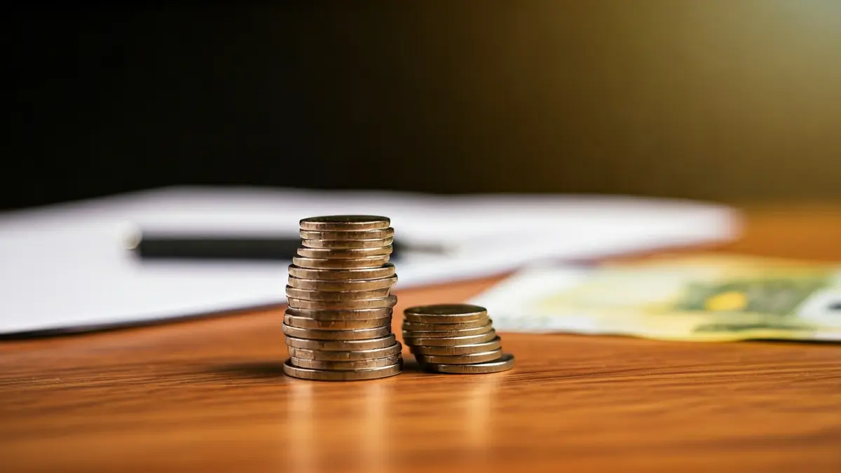 Imatge genèrica de monedes i bitllets d'euro sobre una taula, simbolitzant beneficis financers.