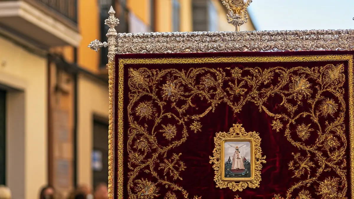 Imatge d'un pendó de comulgars durant una processó festiva en un carrer tradicional.