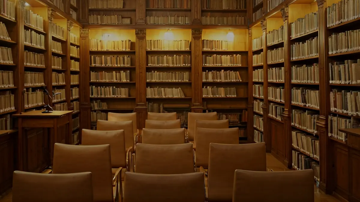 Generic image of a library interior with wooden bookshelves and a podium with a microphone.