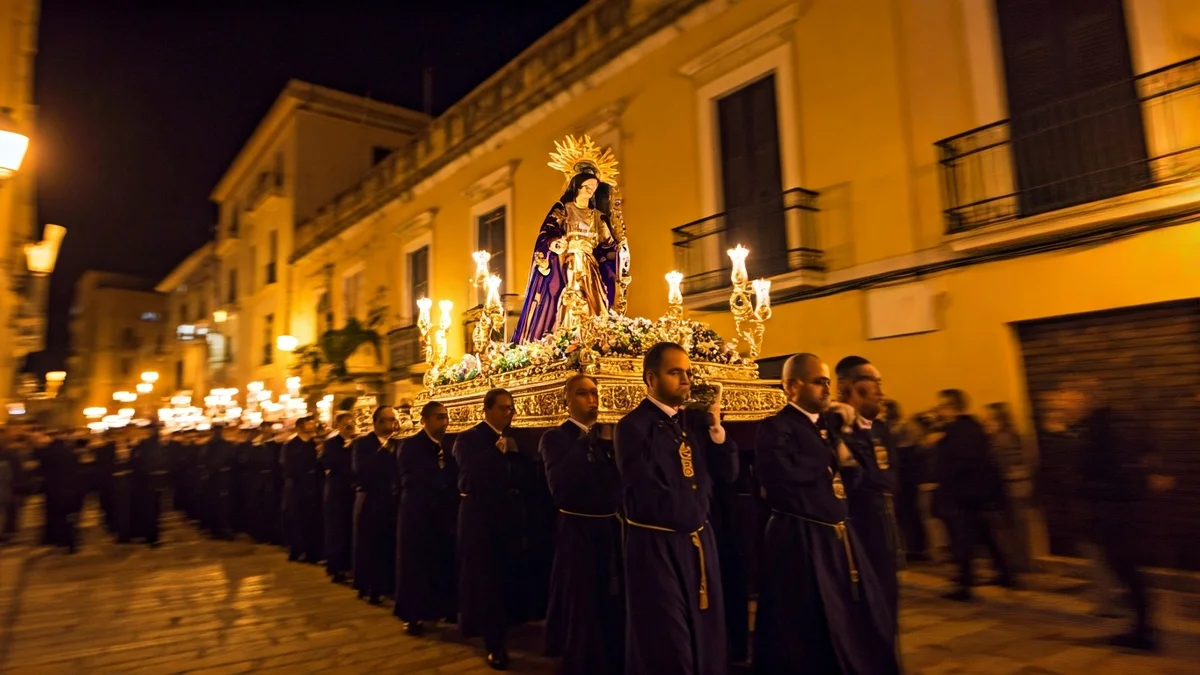 Imatge d'una processó religiosa nocturna amb figures borroses i escultures il·luminades.