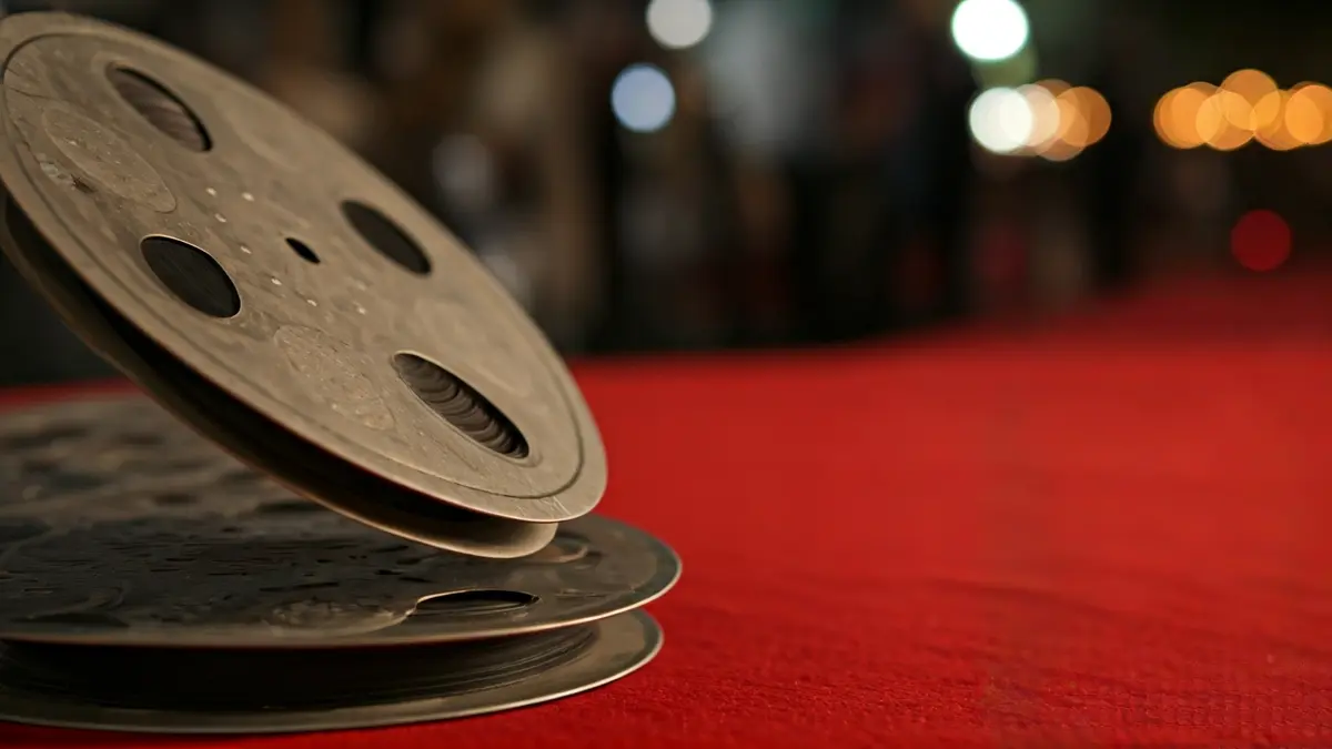 Imagen de un carrete de película con un fondo borroso de una alfombra roja, sugiriendo un festival de cine.