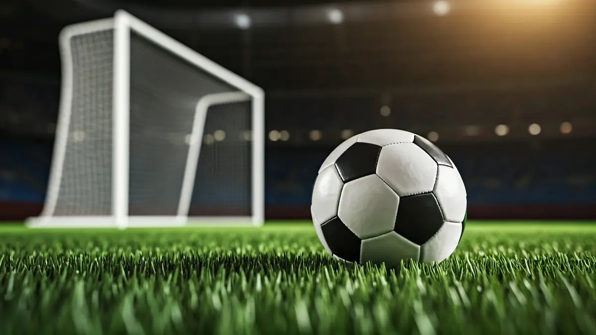 Imatge genèrica d'una pilota de futbol en la gespa d'un camp, amb la porteria desenfocada al fons.