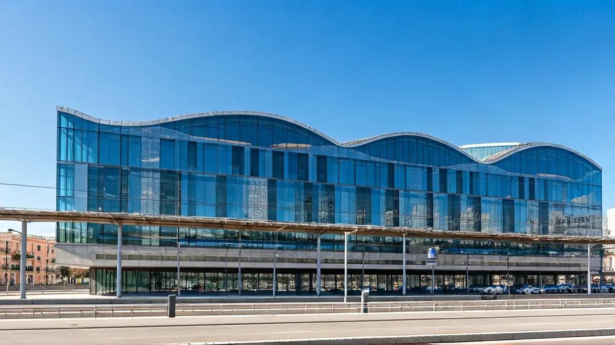 Image of a modern, avant-garde building with large windows, near a train station.