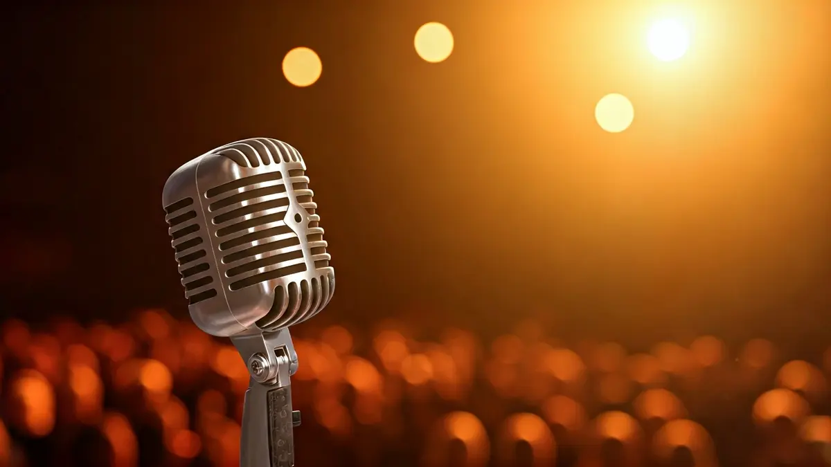 Imatge genèrica d'un micròfon en un escenari, amb instruments musicals desenfocats al fons.