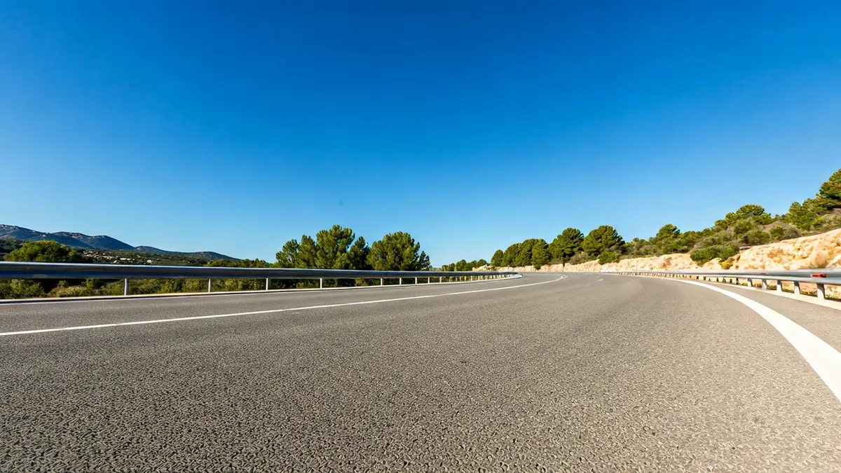 Generic image of a well-maintained asphalt road with clear markings and a Mediterranean landscape.