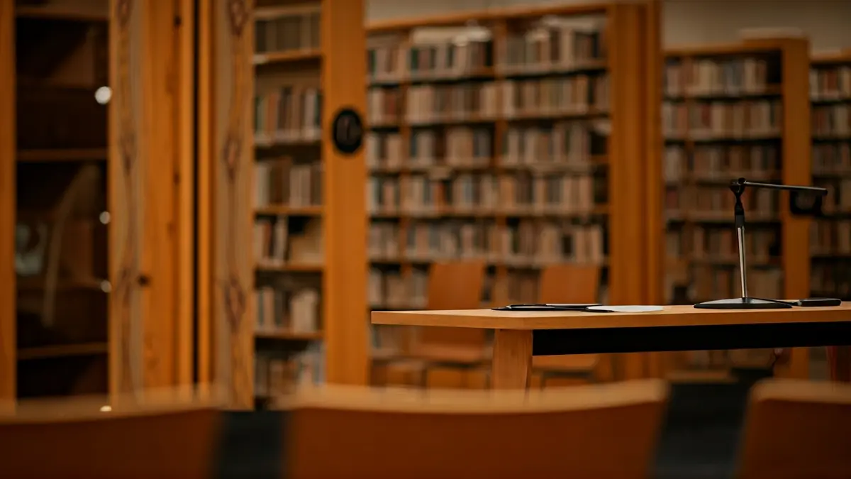 Imagen de un interior de biblioteca con estanterías de madera y un micrófono en un podio.