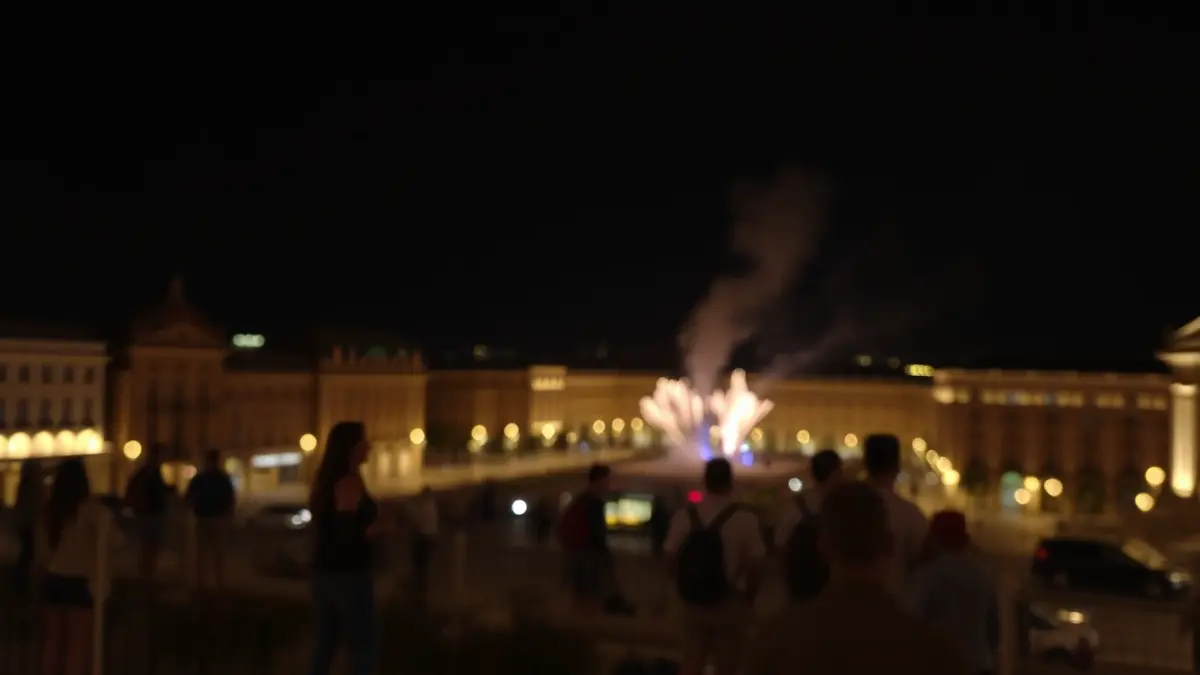 Imatge d'una mascletà nocturna en una plaça de València, amb llums borroses i fum.