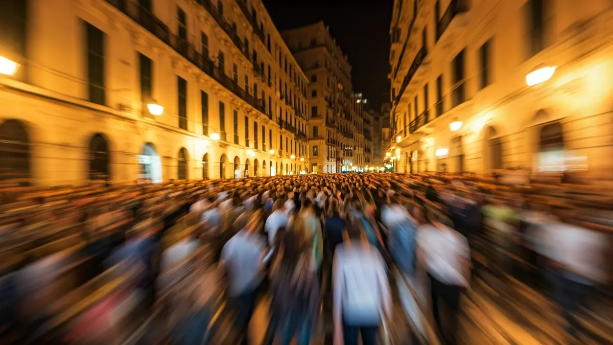 Imatge genèrica d'una multitud borrosa en un carrer de ciutat mediterrània de nit.