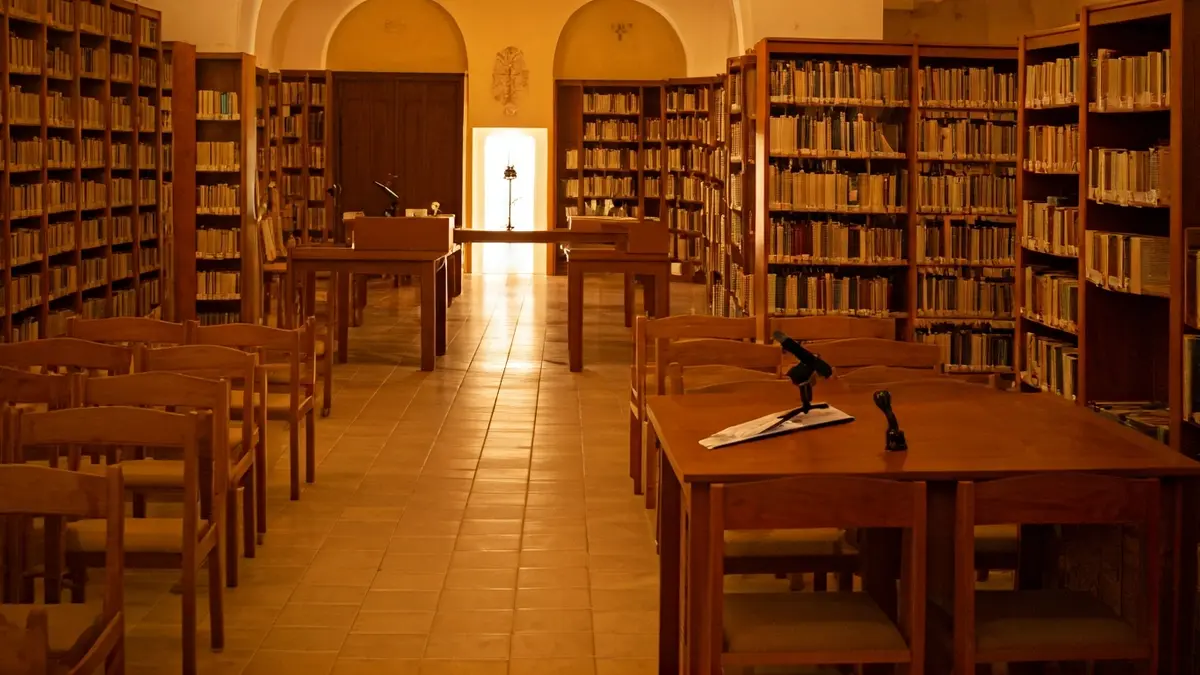 Imagen genérica de una biblioteca con estanterías de madera y un atril con micrófono.
