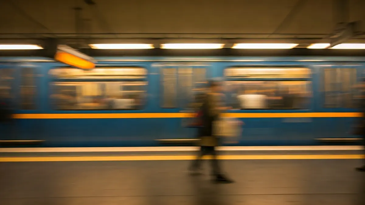 Imagen genérica de un tren de metro llegando a una estación, con luces cálidas y figuras borrosas.