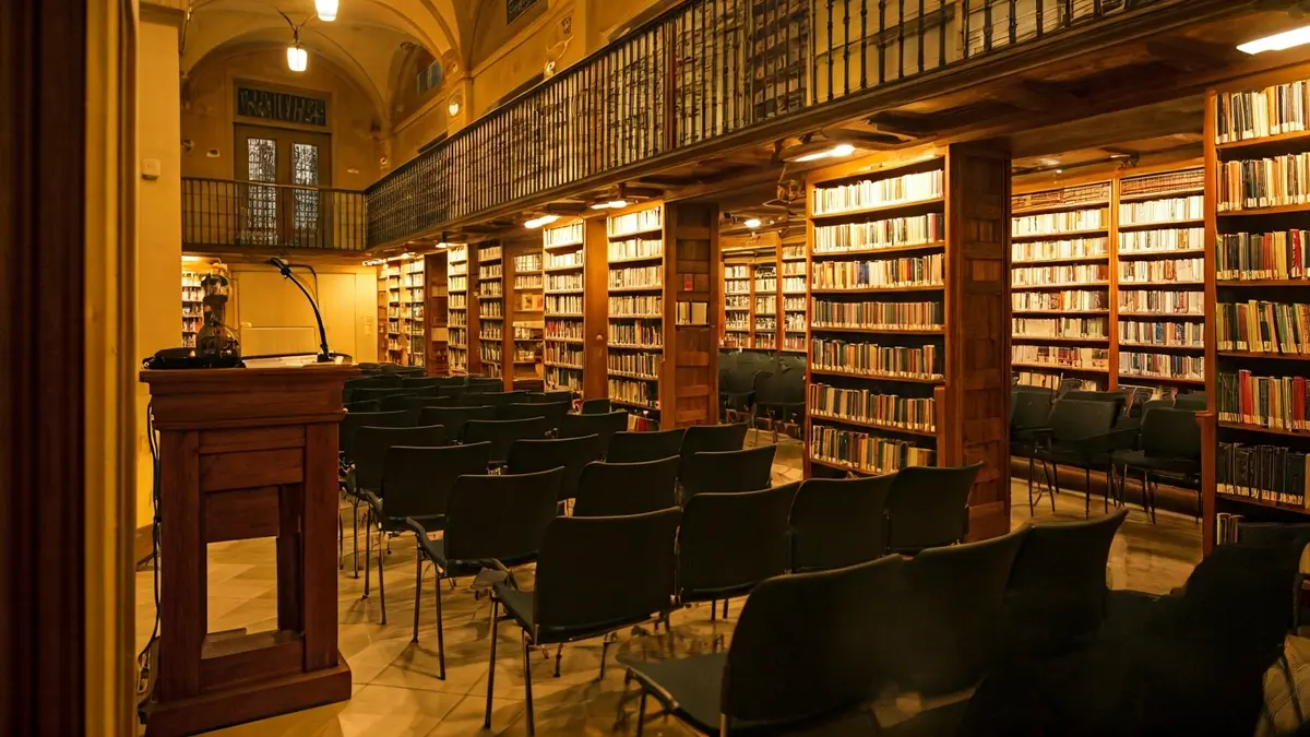 Imatge genèrica d'una biblioteca amb prestatgeries de fusta i un faristol amb micròfon.