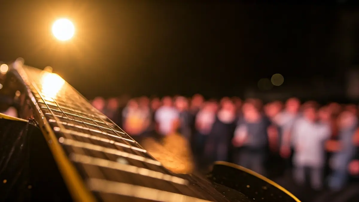 Generic image of an electric guitar on a stage, with warm lights and a blurred audience.