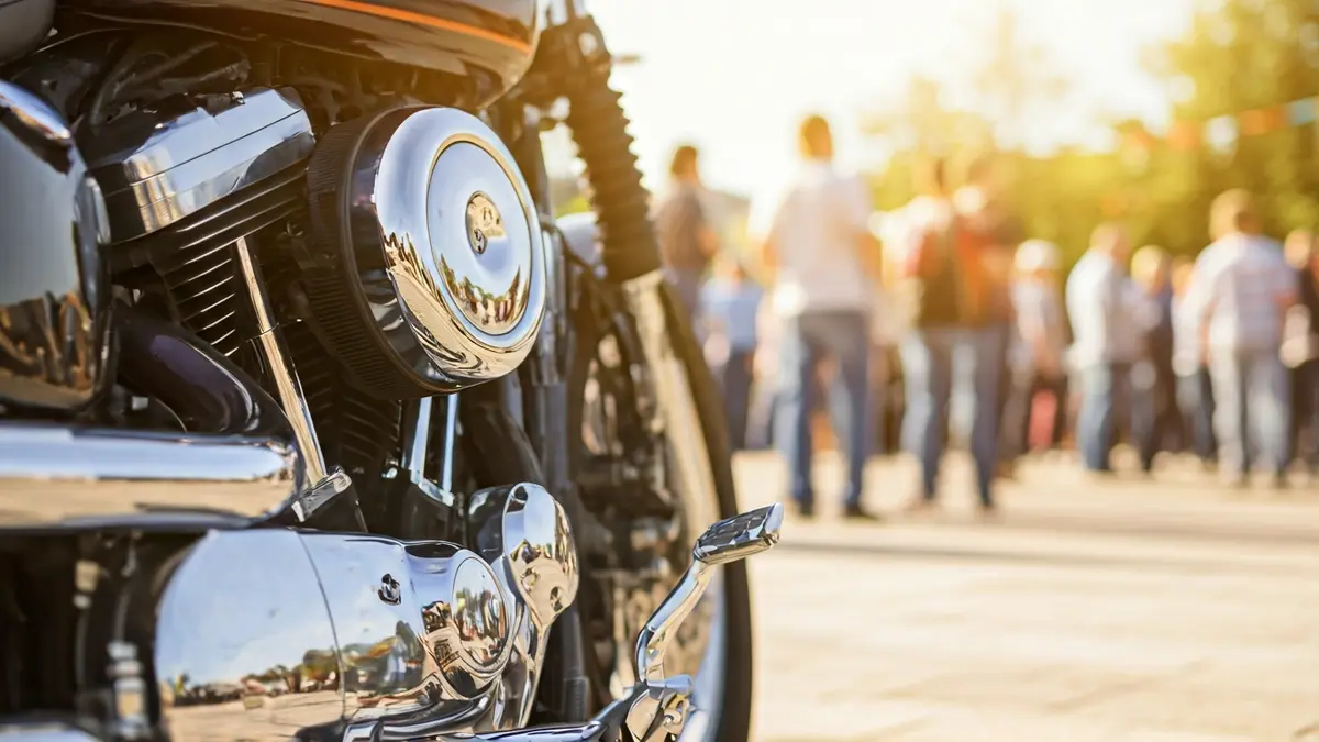 Image of a motorcycle engine with chrome details, with a blurred background of a festive gathering.