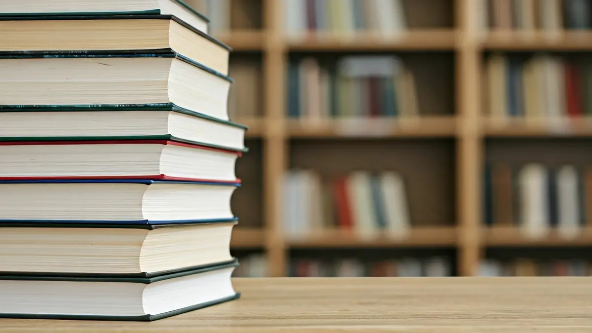 Imatge genèrica de llibres sobre una taula de fusta, amb un fons desenfocat d'una biblioteca o aula.