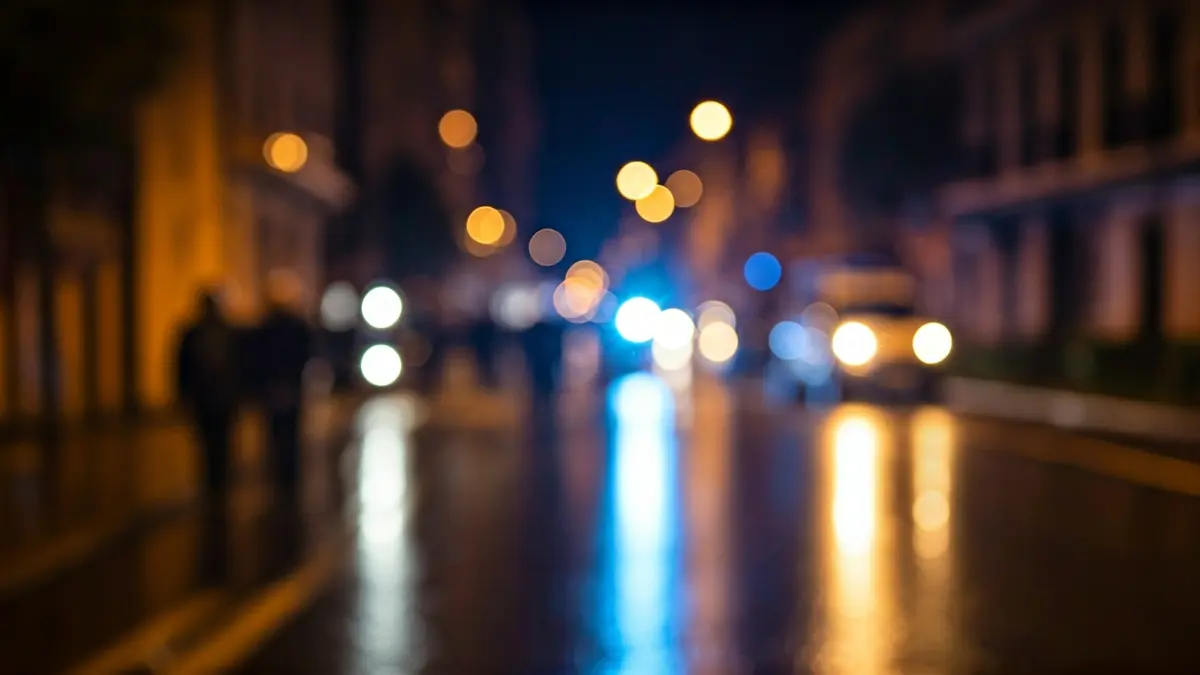 Imatge genèrica de llums d'emergència reflectint-se sobre asfalt mullat de nit.