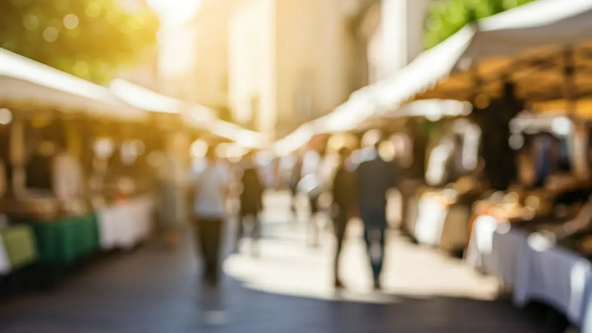 Generic image of a local trade fair in a Mediterranean square, with stalls and people browsing.