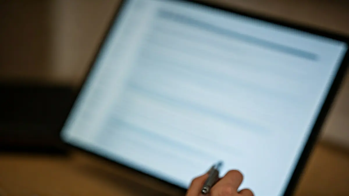 Generic image of a computer screen with tax forms and a hand holding a pen.