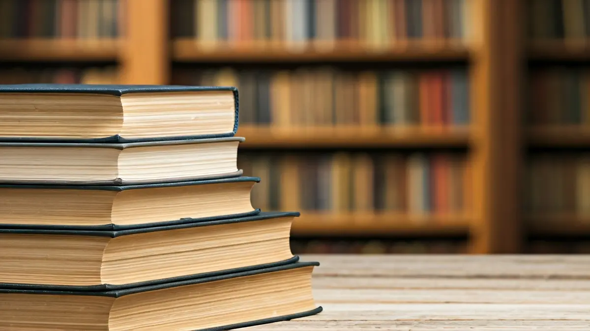 Imagen genérica de libros antiguos en una mesa de madera, con un fondo desenfocado de una biblioteca valenciana.
