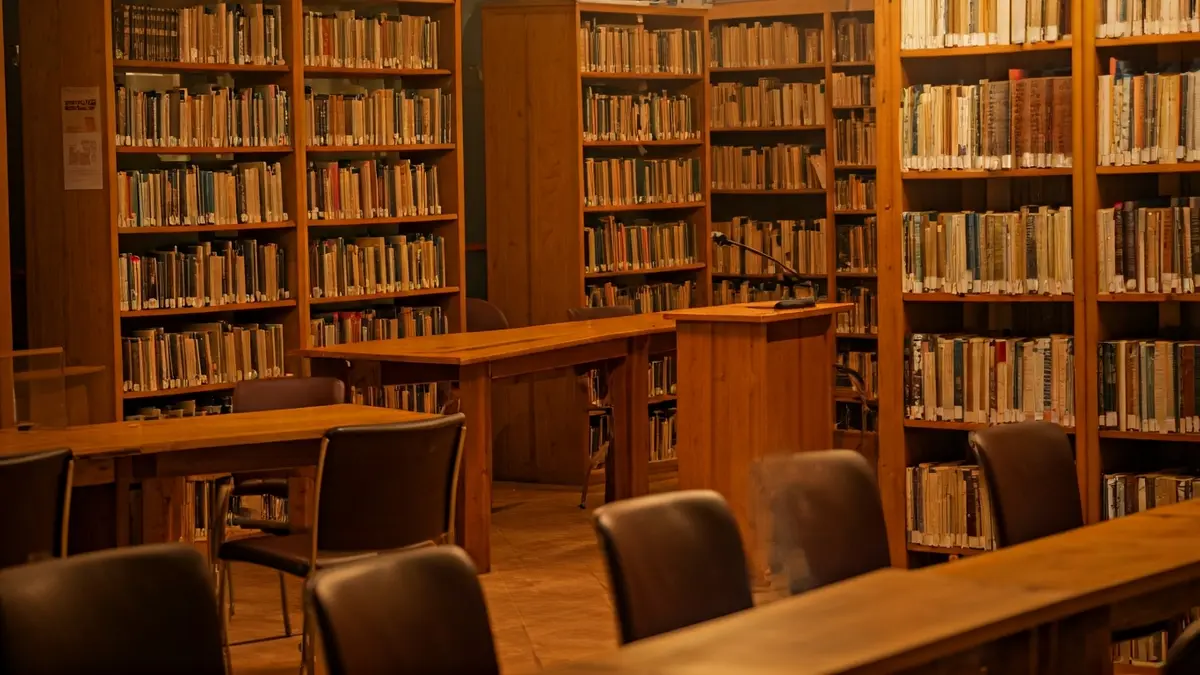 Generic image of a library with wooden bookshelves and a podium with a microphone.