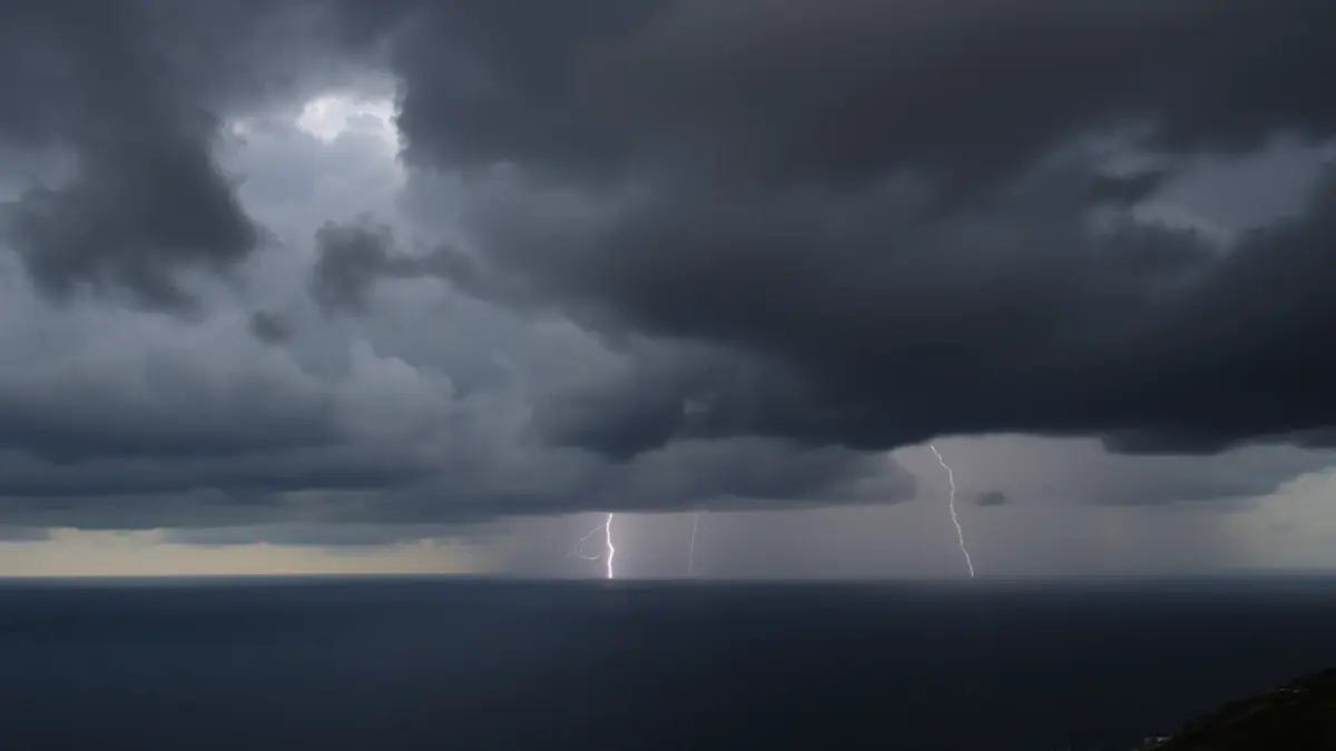 Generic image of dark storm clouds over a Mediterranean coastal landscape with heavy rain.