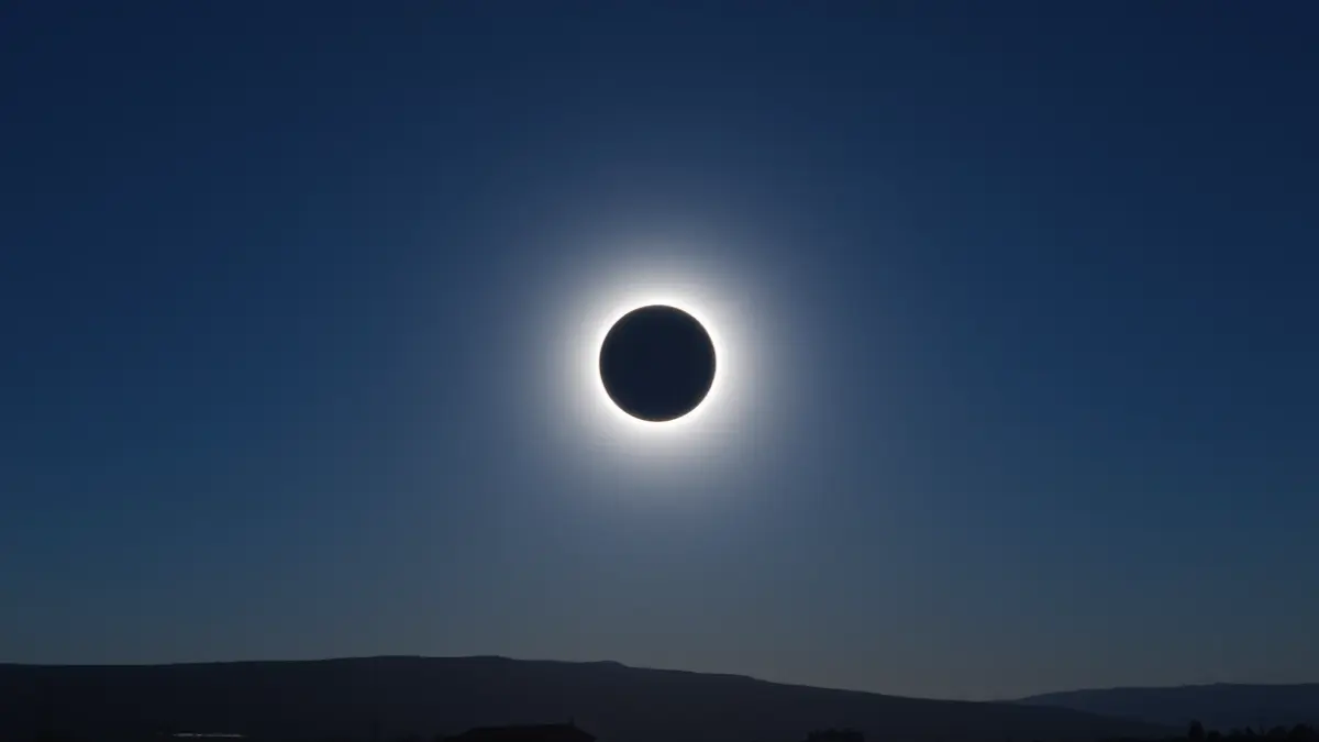 Image of a total solar eclipse, with a dark sky and a corona around the hidden sun. No buildings or people.