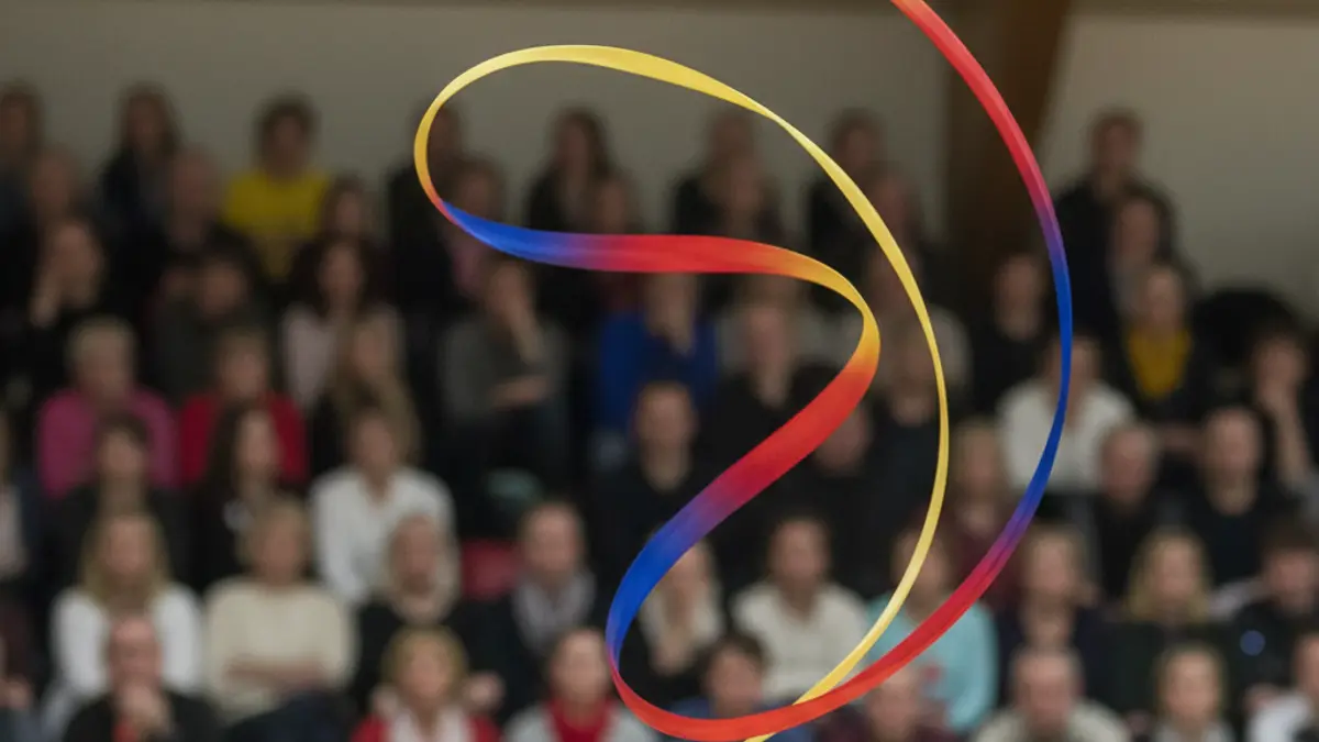 Generic image of a rhythmic gymnastics ribbon in motion, with a blurred gymnasium in the background.