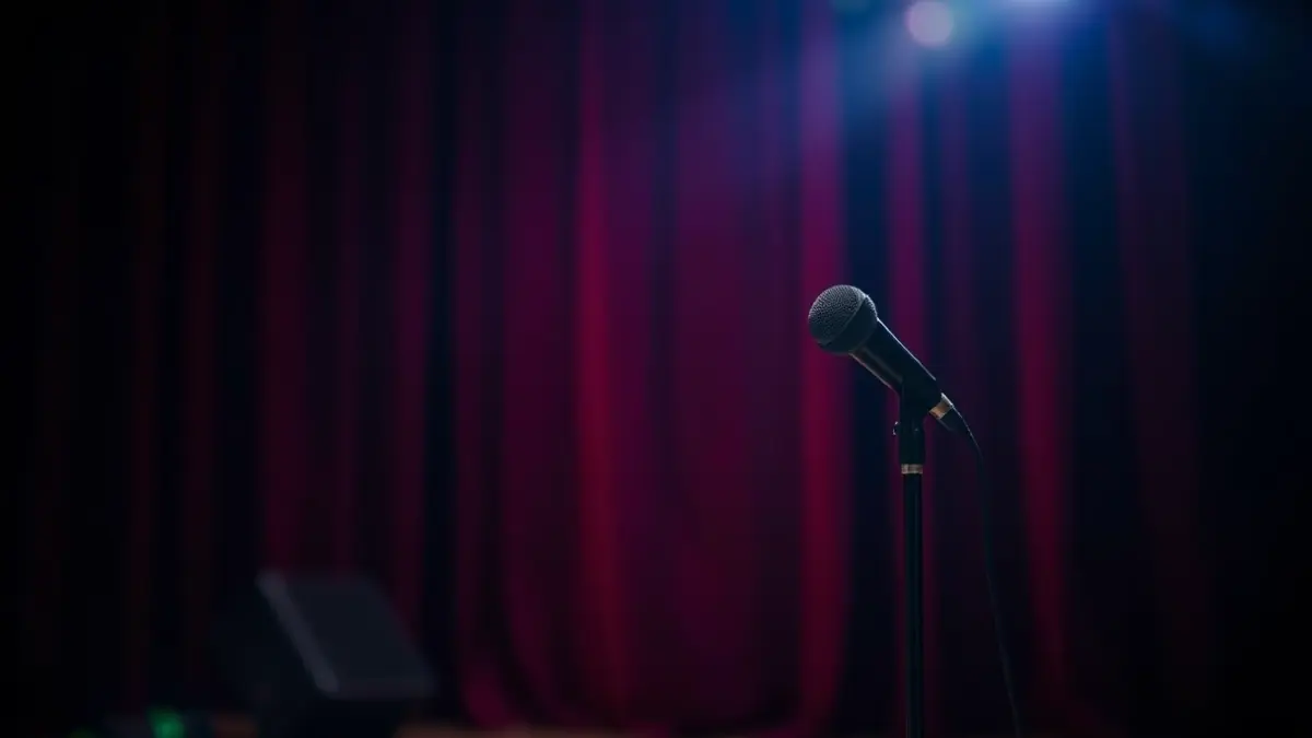 Imatge genèrica d'un escenari teatral amb un micròfon i cortines roges, amb una il·luminació càlida.