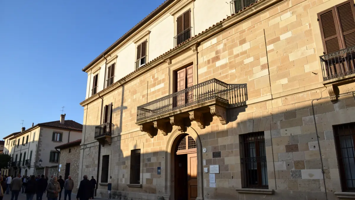 Imatge genèrica d'un ajuntament mediterrani amb balcó i llums càlides.