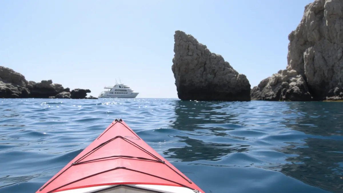 Imagen de un kayak parcialmente hundido cerca del Peñón de Ifach en Calp, con una embarcación de rescate a lo lejos.