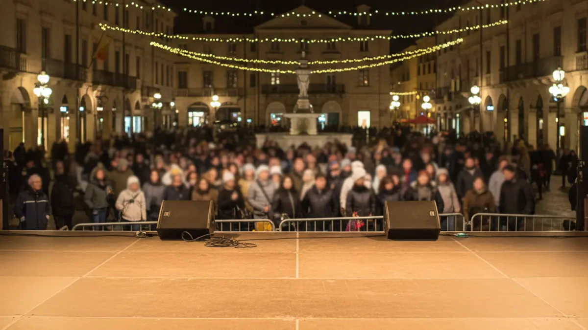 Imagen genérica de un escenario vacío en una plaza de noche, con luces borrosas, antes de una actuación.