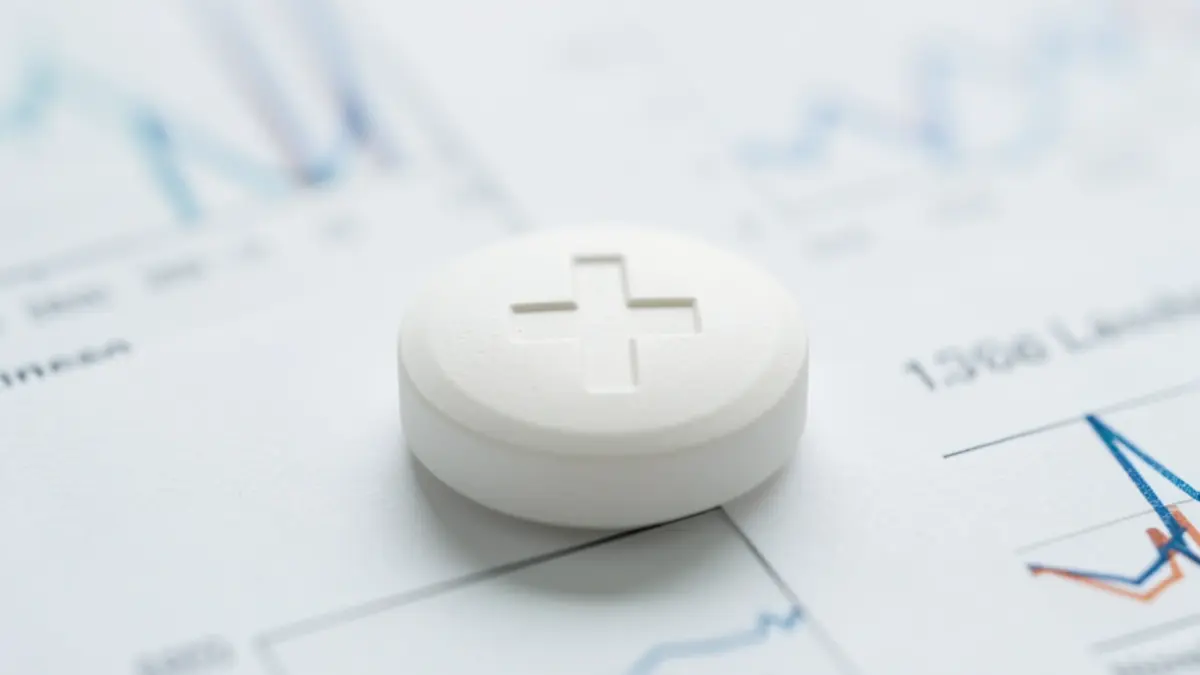 Generic image of a pharmaceutical pill with a blurred medical symbol in the background.